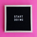 Black letter board with 'Start Doing' motivational text on bright pink background.