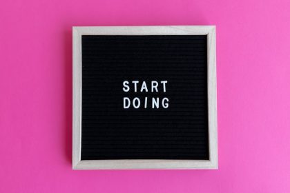 Black letter board with 'Start Doing' motivational text on bright pink background.