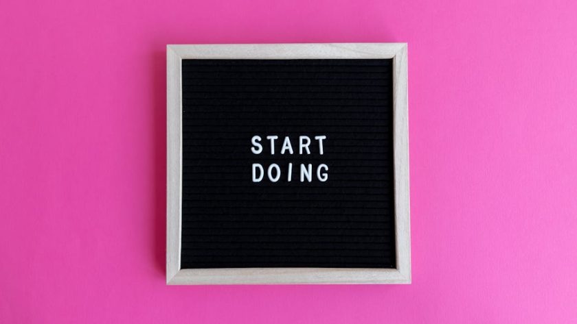 Black letter board with 'Start Doing' motivational text on bright pink background.