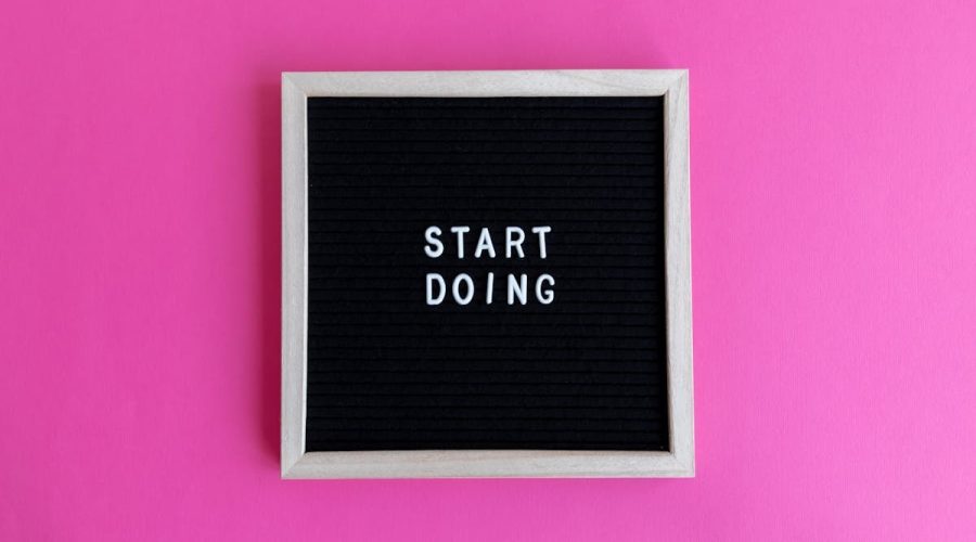 Black letter board with 'Start Doing' motivational text on bright pink background.